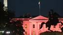 Patung Andrew Jackson terlihat dengan latar belakang Gedung Putih yang diterangi warna pink memperingati bulan kesadaran Kanker Payudara di Washington, DC, AS (1/10). (AFP Photo/Andrew Caballero Reynolds)