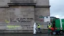 Pekerja membersihkan grafiti bertuliskan 'jaket kuning akan menang' di Arc de Triomphe, Paris, Prancis, Minggu (2/12). Kenaikan pajak bahan bakar memicu kerusuhan di Paris. (AP Photo/Thibault Camus)