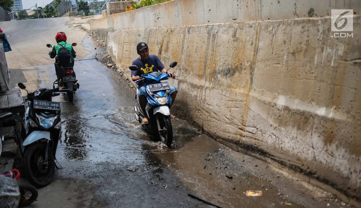 Pengendara melintasi genangan air dekat tanggul pengaman pantai yang bocor di Muara Baru, Jakarta, Selasa (11/12). Tanggul pengaman pantai untuk mencegah banjir rob tersebut bocor karena tingginya volume pasang surut air laut. (Liputan6.com/Faizal Fanani)