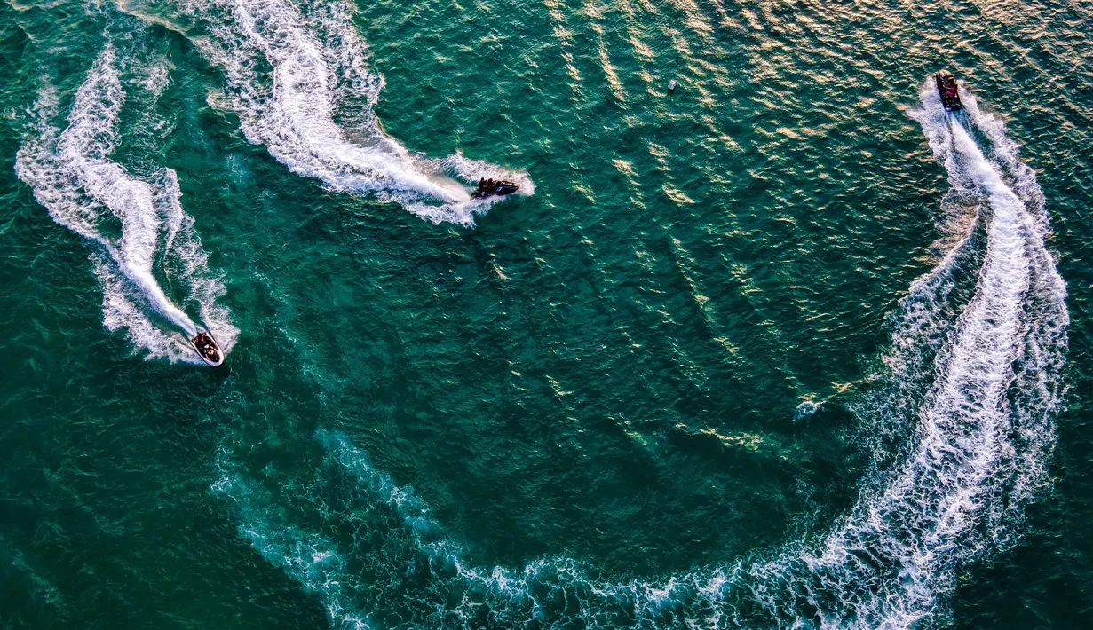 Pantai yang berdekatan dengan kawasan wisata Lampuuk ini menawarkan aktivitas olahraga air, termasuk berenang dan menyelam. Tampak dalam foto, pemandangan udara menunjukkan orang-orang saat berkumpul menikmati masa libur panjang Idulfitri di area olahraga air, Pantai Lhoknga, Aceh, pada Kamis 26 Maret 2026. (Chaideer MAHYUDDIN/AFP)