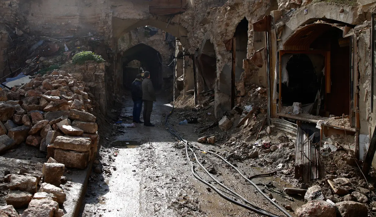 Dua orang pria melihat kondisi bangunan pasar lama di kota tua Aleppo, Suriah (18/1). Perang di Aleppo telah mereda lebih dari setahun yang lalu, namun kondisi bangunan di pasar ini masih belum pulih. (AP Photo/Hassan Ammar)