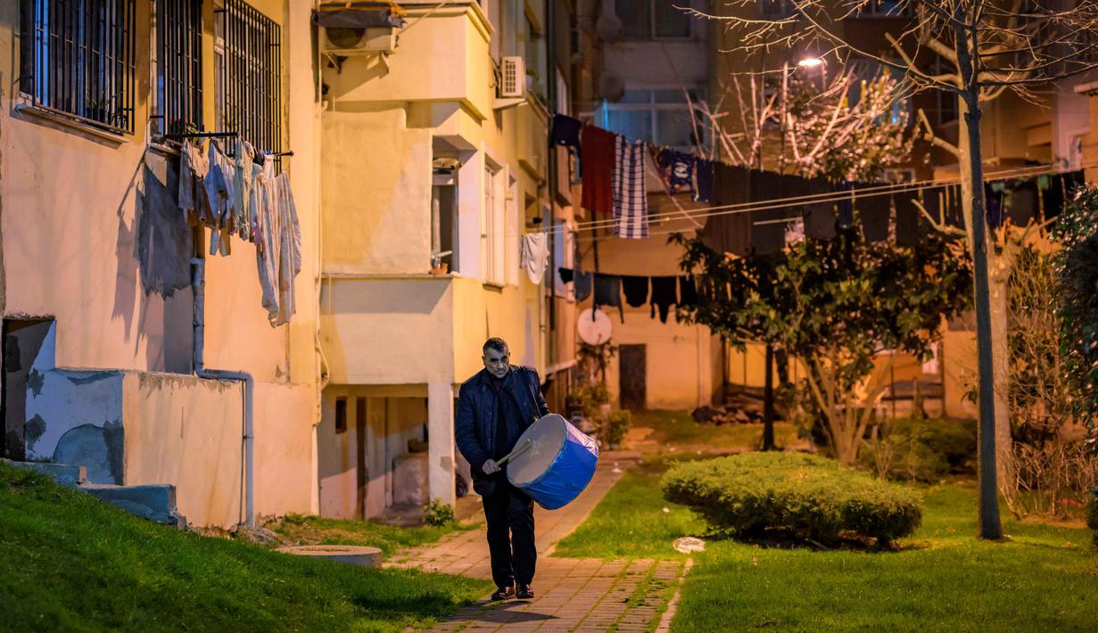 Tradisi ini dimulai di distrik Fatih dekat semenanjung bersejarah Istanbul, tempat sebagian besar penabuh gendang Ramadan saat ini berasal dari komunitas Roma Turki. Tampak dalam foto, seorang pemain drum Turki memainkan drum dan menyanyikan lagu-lagu tradisional di jalanan Istanbul, untuk membangunkan umat Muslim untuk sahur, yaitu makan malam Ramadan, pada 24 Februari 2026. (Yasin AKGUL/AFP)