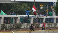 Mahasiswa mengibarkan bendera Merah Putih saat demonstrasi menolak pengesahan RUU KUHP dan revisi UU KPK di depan Gedung DPR, Jakarta, Selasa (24/9/2019). Mahasiswa lari tunggang langgang setelah aparat kepolisian menembakkan gas air mata dan water cannon. (Liputan6.com/JohanTallo)