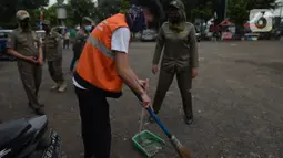 Warga yang tidak memakai masker melakukan sanksi menyapu jalan saat terjaring razia protokol kesehatan COVID-19 di Kebon Nanas, Jakarta, Selasa (15/6/2021). Saat kasus positif Covid-19 di Jakarta meningkat, masih banyak warga yang belum menjalankan protokol kesehatan. (merdeka.com/Imam Buhori)