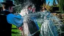 Sejumlah wanita muda disiram air oleh pria berkostum rakyat Szekler Bukovina di Ciko, selatan Budapest, Senin (3/4). Tradisi Paskah populer di Hungaria ini dilakukan pada Senin Paskah yang juga dikenal dengan nama Ducking Monday (Tamas Soki/MTI via AP)