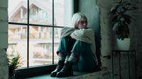 Seorang wanita sedang depresi dan duduk di dekat jendela. (Shutterstock/StockUnit)