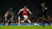 Pemain Arsenal Theo Walcott menggiring bola melewati pemain West Ham United pada laga perempat final Piala Liga Inggris di Emirates Stadium, Selasa (20/12). Gol tunggal Danny Welbeck memberikan Arsenal kemenangan 1-0 atas West Ham. (AP /Alastair Grant)