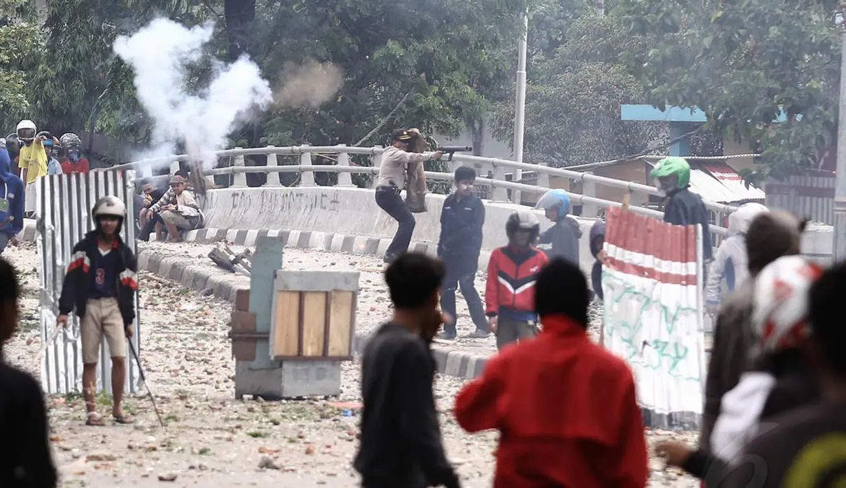 Aparat kepolisian menembakkan gas air mata untuk membubarkan massa yang terlibat bentrok di kawasan Manggarai, Jakarta, Minggu (30/11/2014). (Liputan6.com/Faizal Fanani)