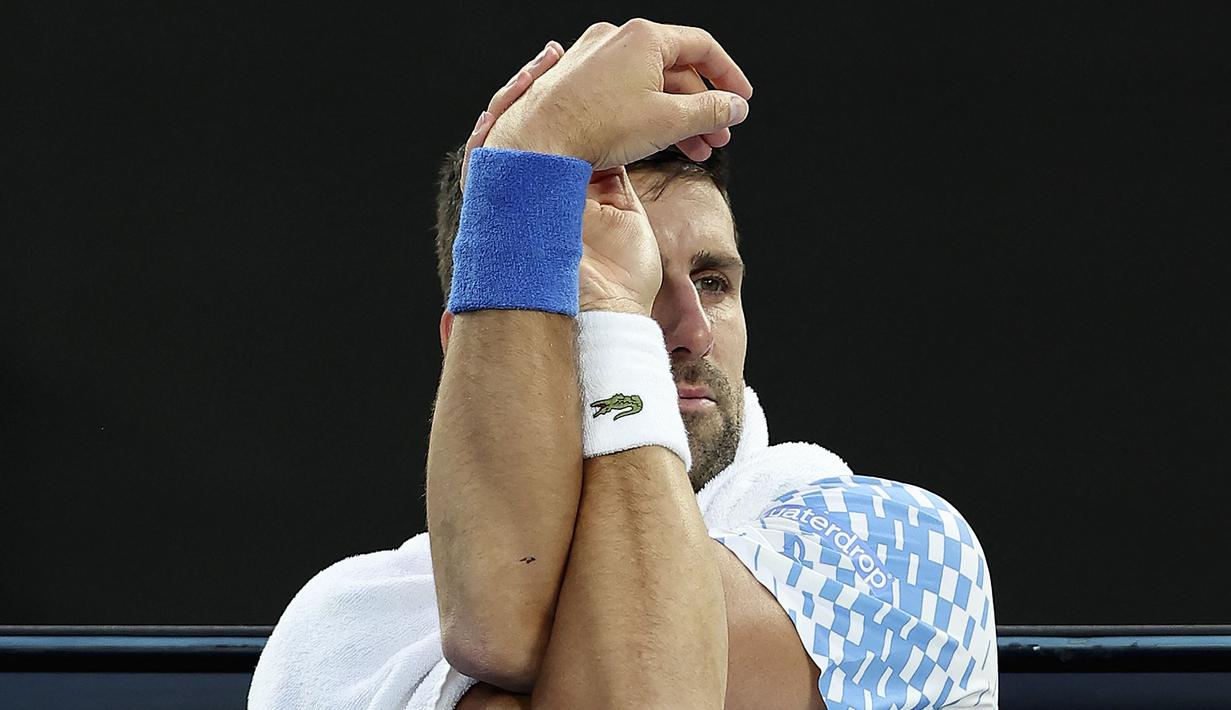 Petenis Serbia, Novak Djokovic melakukan peregangan saat melawan petenis Prancis, Enzo Couacaud pada Australian Open 2023 di Melbourne, Australia, 19 Januari 2023. (AFP/Martin Keep)