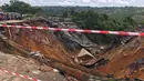 Permukaan jalan ambruk oleh tanah longsor yang disebabkan hujan lebat melanda distrik Lemba, Kinshasa di Republik Demokratik Kongo pada Selasa (26/11/2019). Menurut seorang pejabat terkemuka di Kota Kinshasa, ada tiga puluh enam orang tewas tertimbun tanah longsor. (AFP/Ange Kasongo)
