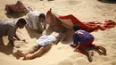 Pekerja membantu seorang pria untuk dikubur dengan pasir gurun di Siwa, Mesir, 12 Agustus 2015. Terapi mengubur diri di dalam pasir gurun saat terik matahari diyakini dapat menyembuhkan rematik, sakit sendi, dan impotensi seksual. (REUTERS/Asmaa Waguih)