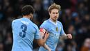 Pemain Manchester City, Ruben Dias (kiri), memberikan ban kapten kepada rekannya yakni Kevin De Bruyne saat memasuki lapangan pada menit ke-57 dalam pertandingan putaran ketiga Piala FA melawan Huddersfield Town yang berlangsung di Etihad Stadium, Manchester, Minggu (7/1/2024). (AFP/Paul Ellis)