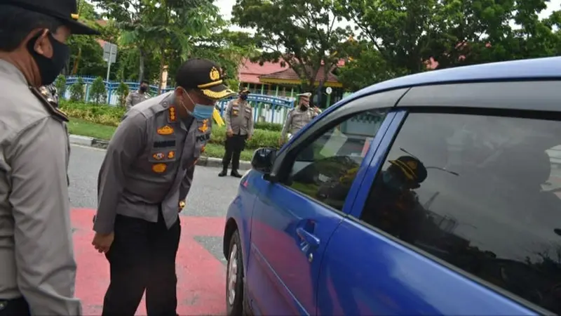 Polisi mengecek penumpang di Pekanbaru karena pemberlakuan pembatasan sosial.