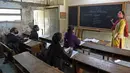 Siswa dengan masker menghadiri kelas saat sekolah dibuka kembali setelah ditutup hampir sembilan bulan karena pandemi COVID-19 di Ahmedabad, India, Senin (11/1/2021). Negara bagian Gujarat telah membuka kembali sekolah hanya untuk kelas 10 dan 12. (Sam PANTHAKY / AFP)