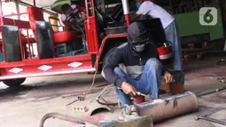 Pekerja melakukan pengelasan saat pembuatan mobil wisata Odong-Odong di bengkel perakitan milik Didik Hermawan di Jurangmangu, Tangerang Selatan, Sabtu (27/2/2021). Dalam sebulan, bengkel tersebut bisa menjual empat hingga lima unit odong-odong. (Liputan6.com/Angga Yuniar)