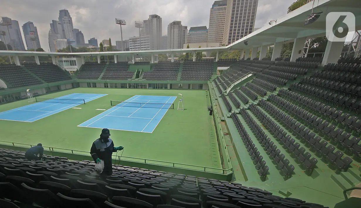 Petugas menyemprotkan cairan disinfektan pada bangku penonton di Lapangan Tennis Outdoor, Kompleks Olahraga GBK (Gelora Bung Karno), Senayan, Jakarta, Kamis (19/3/2020). Penyemprotan untuk mencegah penyebaran Virus Corona Covid-19 di Lingkungan Kompleks Olahraga GBK. (Liputan6.com/Herman Zakharia)