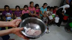 Anak-anak Palestina mengantre untuk makanan buka puasa gratis di sebuah dapur amal, kota Hebron, Tepi Barat, Minggu (20/5). Dapur amal yang dikelola Wakaf Islam itu dinilai sangat membantu dalam mencukupi gizi selama bulan Ramadan tiba. (AFP/HAZEM BADER)