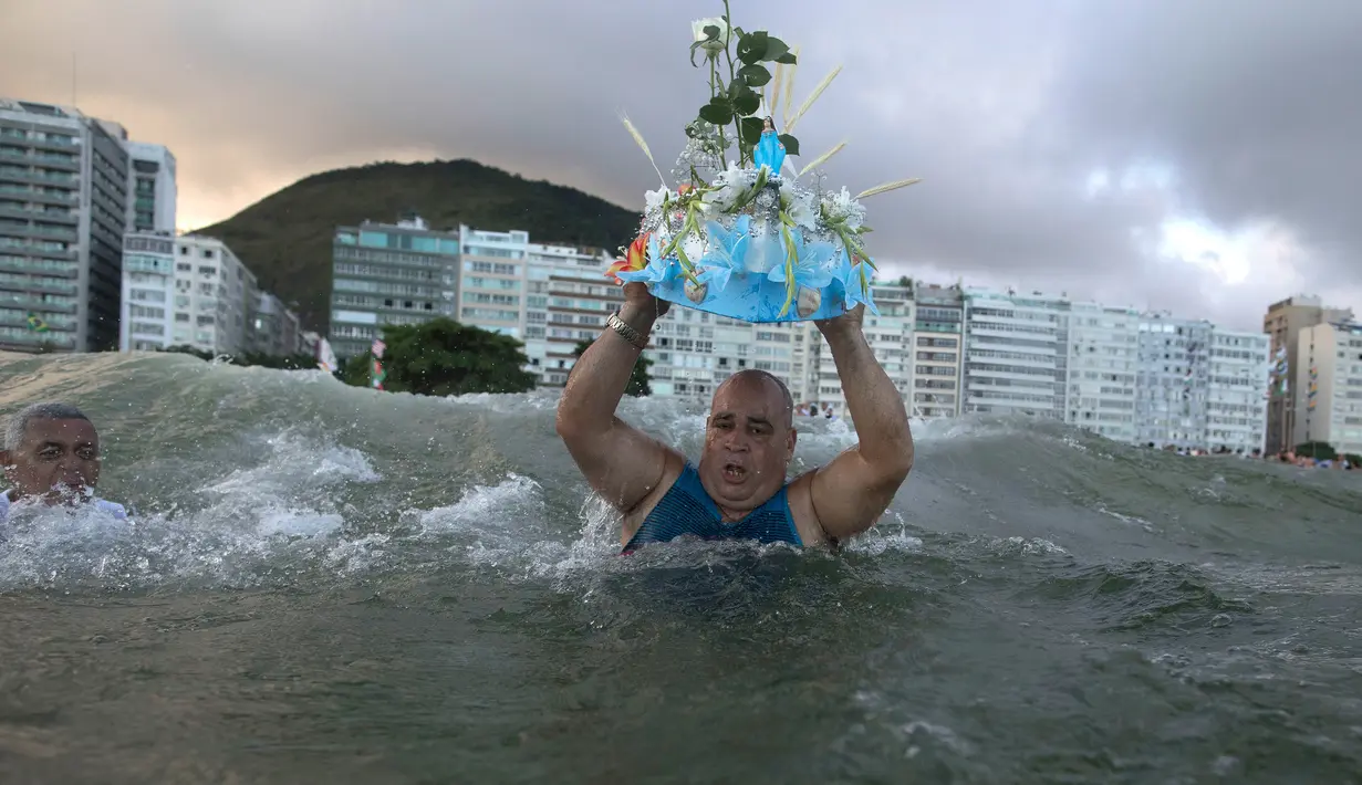 Penganut kepercayaan Afro-Brasil membawa persembahan untuk Dewi Laut, Yemanja dalam tradisi upacara menjelang tahun baru di pantai Copacabana, Rio de Janeiro, Sabtu (29/12). Mereka melarung sesaji sebagai bentuk syukur kepada dewi laut. (AP/Leo Correa)