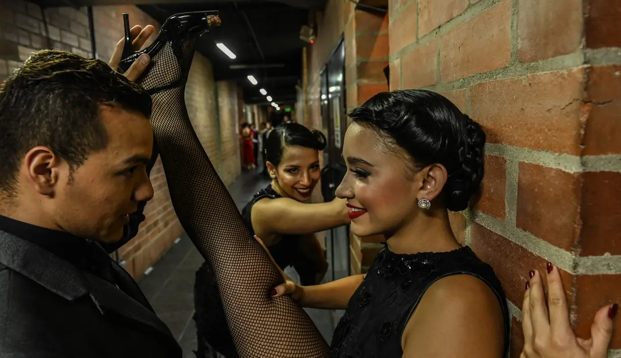 Penari melakukan pemanasan di belakang panggun sebelum tampil dalam Turnamen Menari Tango di Festival Tango Internasional XIII di Medellin, Kolombia (18/6/2019). Festival Tango ini berlangsung dari 16 sampai 24 Juni 2019. (AFP Photo/Joaquin Sarmiento)