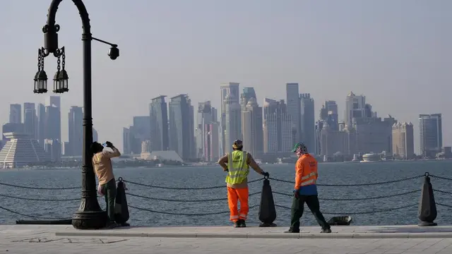 With the city skyline in the background, migrant workers rest at the Doha port, in Doha, Qatar, Sunday, Nov. 13, 2022.