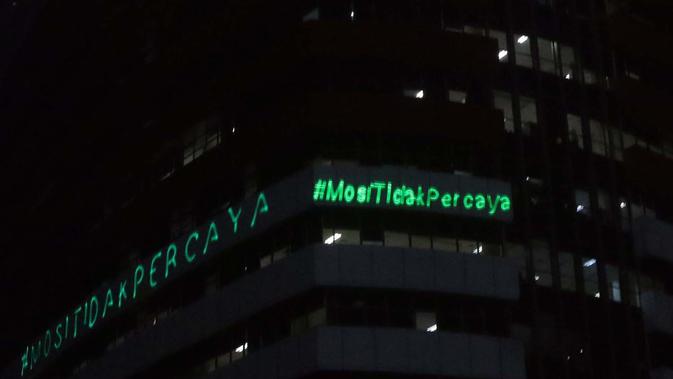 Aktivis Greenpeace menembakkan sinar laser bertuliskan Mosi Tidak Percaya ke gedung Merah Putih KPK, Jakarta, Senin (28/6/2021) malam. Aksi tersebut sebagai bentuk keprihatinan atas upaya pelemahan KPK sejak disahkannya Revisi UU KPK hingga Tes Wawasan Kebangsaan. (Liputan6.com/Helmi Fithriansyah)