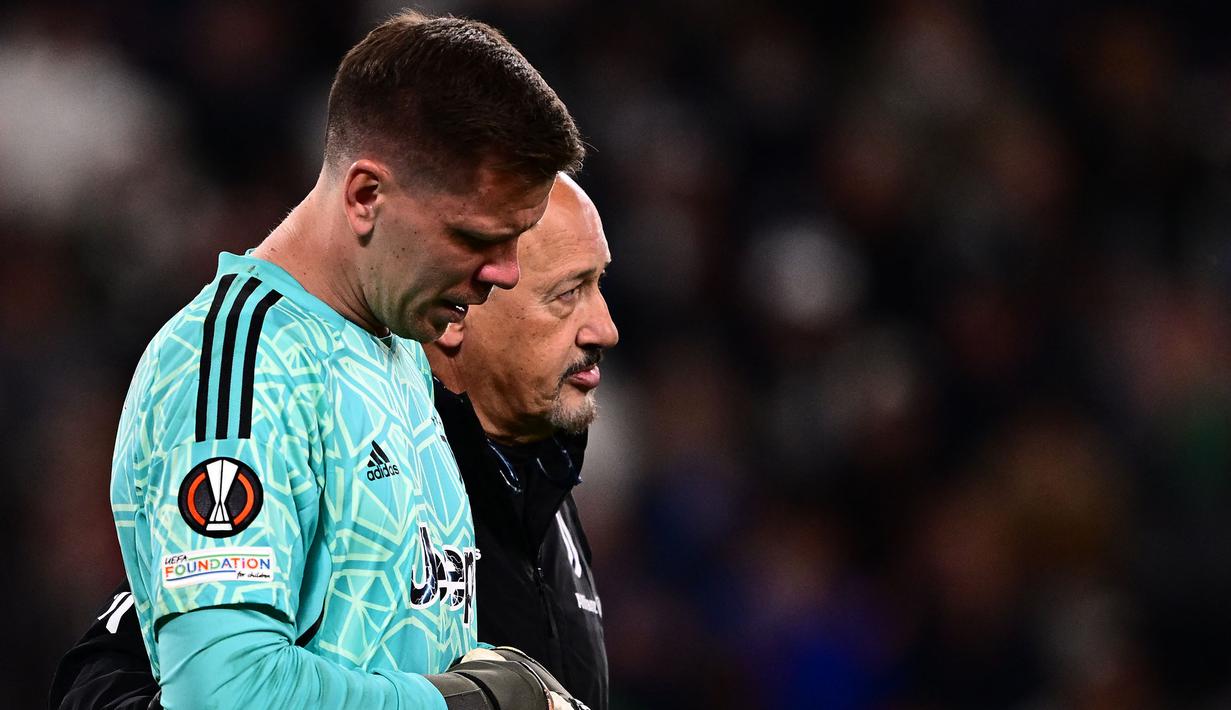 Kiper Juventus, Wojciech Szczesny berjalan meninggalkan lapangan dibantu oleh tim medis setelah mengalami sakit dada ketika pertandingan leg pertama perempat final Liga Europa 2022/2023 melawan Sporting CP di Allianz Stadium, Turin, Jumat (14/04/2023). Szczesny diketahui terkena paltisipasi jantung atau kondisi di mana seseorang merasakan kerja jantung yang kuat, cepat, atau tidak teratur. (AFP/Marco Bertorello)