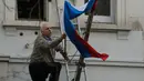 Aksi seorang pria melepaskan bendera nasional Rusia dari tiang di luar Kedutaan Besar Rusia di London, Rabu (14/3). Inggris diketahui mengusir 23 diplomat Rusia menyikapi kasus mantan agen ganda Rusia yang diduga diracuni zat syaraf. (AP/Alastair Grant)