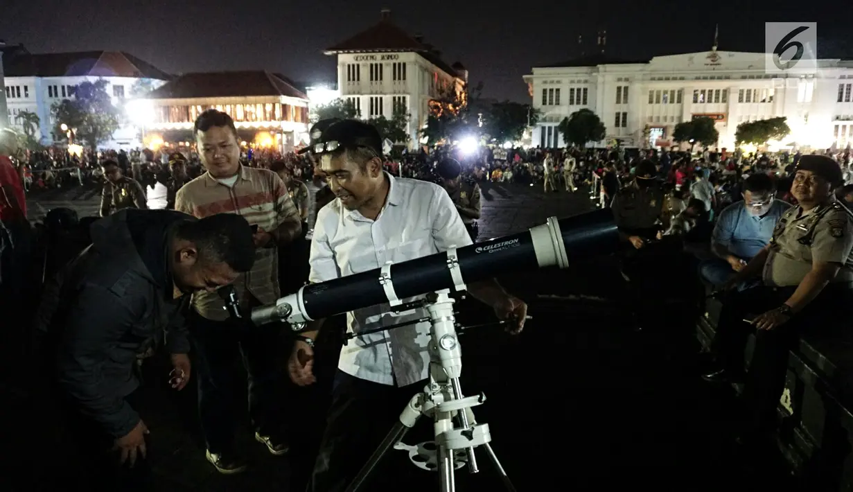 Warga menyaksikan gerhana bulan total lewat teleskop di Kota Tua Jakarta, Rabu (31/1). Selain menyediakan layar lebar, tiga unit teleskop disediakan untuk melihat fenomena super blue blood moon. (Liputan6.com/Arya Manggala)