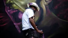 Seorang seniman yang bernama Montalvo Tekuene melewati salah satu karya grafiti dalam festival pekan grafiti di Mexico City, Meksiko, Minggu (9/10). Grafiti merupakan salah satu seni jalanan yang populer hingga kini. (REUTERS/Carlos JASSO)