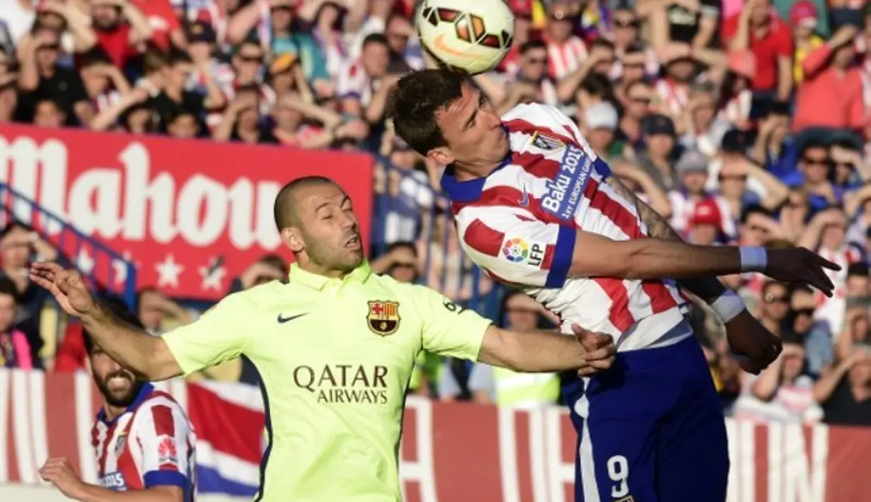 Pemain Barcelona, Javier Mascherano (kiri) berebut bola dengan striker Atletico Madrid, Mario Mandzukic. (AFP PHOTO / GERARD JULIEN)
