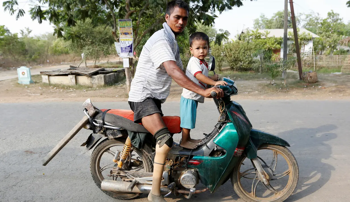 Aung Than Oo bersama anaknya di atas sepeda motor di Yangon, Myanmar, 3 Juni 2016. Sejumlah mantan tentara Myanmar tetap menjalani kehidupan yang sederhana dengan kaki yang tidak lagi sempurna akibat menginjak ranjau saat bertugas. (REUTERS/Soe Zeya Tun)