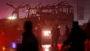 Polisi Afghanistan berjaga-jaga di dekat bangkai minibus yang meledak di dekat Kedubes Rusia di Kabul, Rabu (20/1). Ledakan itu menimbulkan asap hitam, sementara ambulans dan mobil pemadam kebakaran segera dikerahkan ke lokasi. (REUTERS/Omar Sobhani)