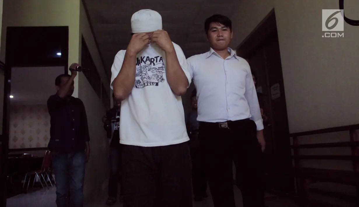 Salah satu tersangka dikawal petugas sebelum konferensi pers terkait narkoba di  Polda Gorontalo, Senin (13/5/2019). Dari tangan WR yang teridentifikasi merupakan oknum staf di salah satu Politeknik di Gorontalo, polisi mengamankan narkoba jenis sabu-sabu. (Liputan6.com/Arfandi ibrahim)