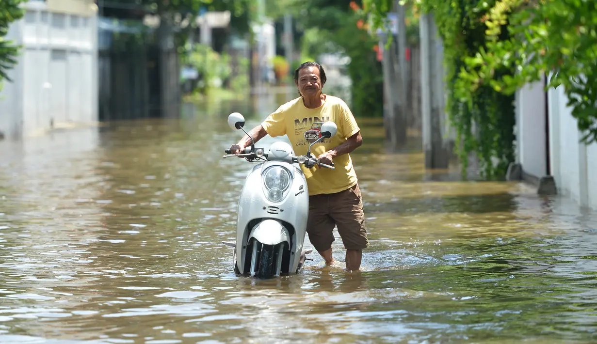 Seorang pria mendorong sepeda motor di sebuah jalan yang terendam banjir pascahujan lebat di Bangkok, Thailand (31/8/2020). (Xinhua/Rachen Sageamsak)