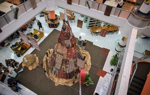 Salah satu mahasiswa berdiri di samping instalasi dekorasi berbentuk pohon Natal dengan motif budaya Papua di Perpustakaan Petra Christian University (PCU), Surabaya, Jawa Timur, Kamis 18 Desember 2025. Jelang perayaan Natal 2025, perpustakaan Petra Christian University (PCU) kembali menghadirkan instalasi dekorasi Pohon Natal tematik. (JUNI KRISWANTO/AFP)