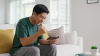 Ilustrasi seorang pria bermain game mobile. (Shutterstock/Chay_Tee)