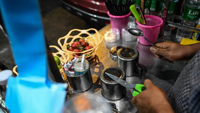 Pedagang kaki lima memukul cangkir logam untuk membuat keributan setelah seruan untuk protes keluar di media sosial di Yangon, Myanmar, 3 Februari 2021. Kudeta militer Myanmar terus memicu protes warga dengan membunyikan klakson mobil, menyalakan lampu ponsel, dan memukul-mukul panci. (STR/AFP)