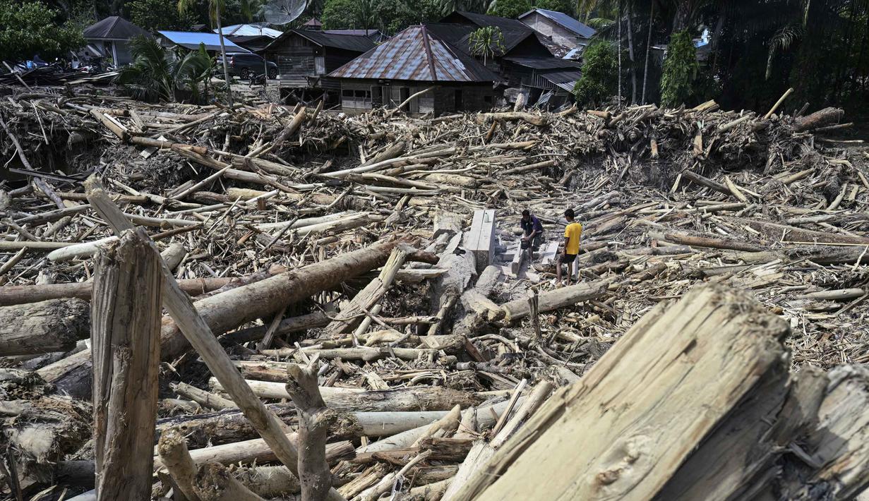 Warga desa memotong kayu-kayu yang hanyut oleh banjir bandang di Garoga, Provinsi Sumatera Utara, pada Kamis 4 Desember 2025. Banjir bandang di Desa Aek Garoga, Kecamatan Batang Toru, Tapanuli Selatan, Sumatera Utara, yang terjadi pada akhir November 2025 lalu membawa serta kayu-kayu gelondongan dalam jumlah besar. (YT HARIONO/AFP)