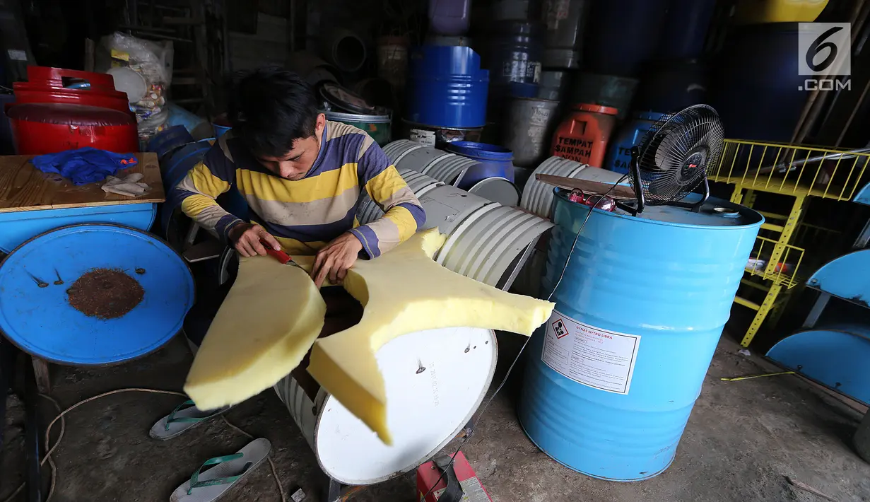 Pekerja sedang memotong busa untuk bangku drum bekas di industri kecil Ali Kreatif, Parung Bogor, Selasa (30/1). Industri yang beromset 20 juta rupiah setiap minggunya juga memproduksi tempat sampah, lemari hingga meja. (Liputan6.com/Fery Pradolo)