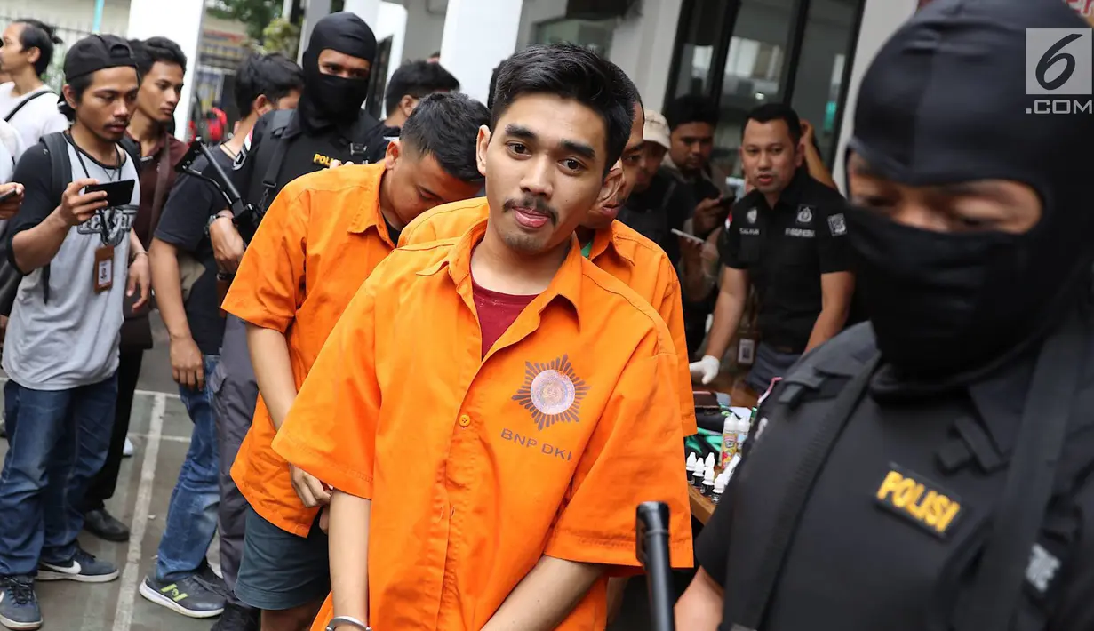 Subdit I Ditresnarkoba Polda Metro Jaya mengawal tersangka kasus jual beli narkoba liquid vape di Jakarta, Kamis (25/10). Subdit I Ditresnarkoba Polda Metro Jaya menangkap tiga pria berinisial ER, AG, dan TM. (Liputan6.com/Immanuel Antonius)