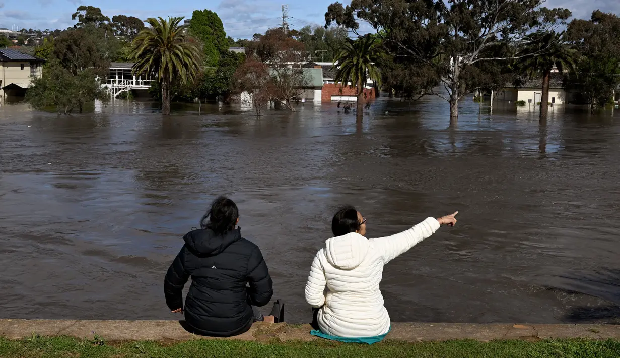Orang-orang melihat daerah banjir di pinggiran Kota Melbourne, Maribyrnong, Australia, Jumat (14/10/2022). ABC menyebut fenomena di Victoria terjadi sekali tiap 200 tahun sekali. (William WEST/AFP)