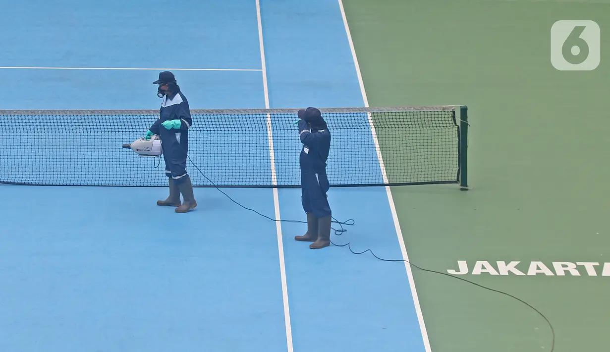 Petugas menyemprotkan cairan disinfektan pada area Lapangan Tennis Outdoor di Kompleks Olahraga GBK (Gelora Bung Karno), Senayan, Jakarta, Kamis (19/3/2020). Penyemprotan untuk mencegah penyebaran Virus Corona Covid-19 di Lingkungan Kompleks Olahraga GBK. (Liputan6.com/Herman Zakharia)