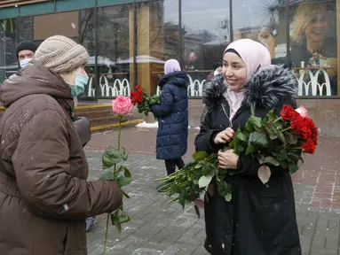 Seorang aktivis berhijab memberikan bunga kepada seorang perempuan pejalan kaki untuk memperingati World Hijab Day atau Hari Hijab Sedunia di Kyiv, Ukraina, Senin (1/2/2021). Hari Hijab Sedunia merupakan gagasan Nazma Khan di New York, Amerika Serikat pada tahun 2013. (AP Photo/Efrem Lukatsky)