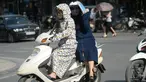 Seorang wanita pengendara motor dan rekannya menggunakan pakaian pelindung saat melintasi pusat kota Hanoi, Rabu (15/6). Vietnam menghadapi gelombang panas dengan suhu hingga mencapai 40 derajat celcius. (Hoang DINH NAM/AFP)