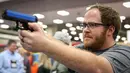Seorang pria menjajal pistol di Kay Bailey Hutchison Convention Center saat konvensi tahunan NRA, Texas (6/5). Acara pameran senjata ini dihadiri sekitar 70.000 peserta. (AFP/Loren Elliot)