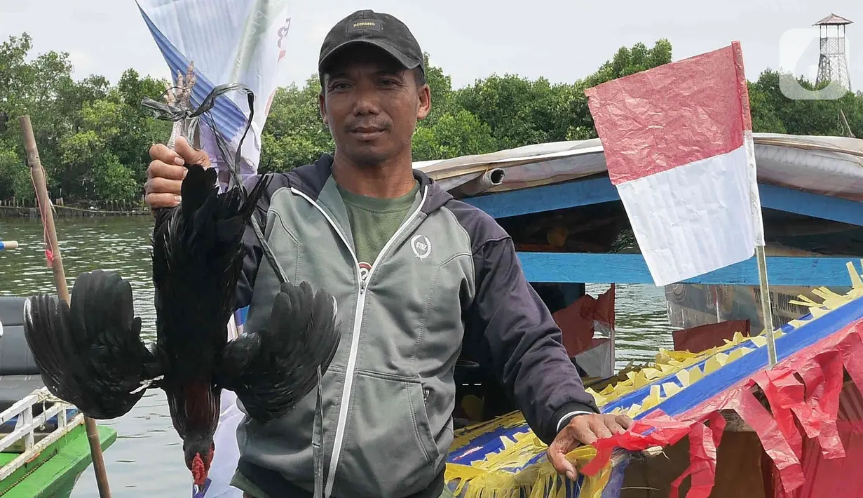 Nelayan menunjukkan sesaji saat bersiap melarung replika kapal di Pantai Tarumajaya, Kabupaten Bekasi, Jawa Barat, Jumat (28/1/2022). Ritual dilakukan sebagai bentuk rasa syukur kepada Tuhan atas berlimpahnya hasil laut. (Liputan6.com/Herman Zakharia)