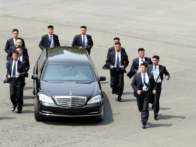 Para pengawal berlari di samping mobil yang membawa Pemimpin Korea Utara Kim Jong-un saat akan makan siang dalam KTT Korea Selatan-Korea Utara di zona demiliterisasi, Panmunjom, Korea Selatan, Jumat (27/4). (Korea Summit Press Pool/AFP)