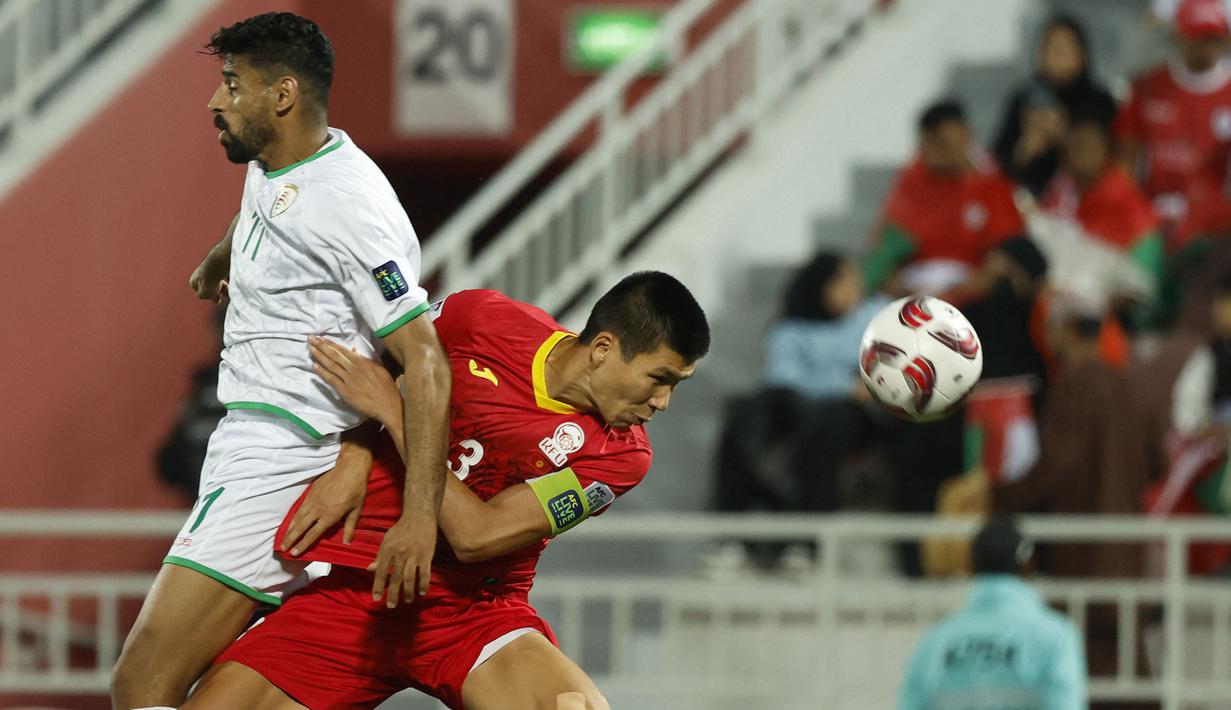 Striker Timnas Oman, Muhsen Al Ghassani (kiri) berebut bola dengan bek Kirgistan, Tamirlan Kozubaev pada laga ketiga Grup F Piala Asia 2023 di Abdullah bin Khalifa Stadium, Doha, Qatar, Kamis (25/1/2024). (AFP/Karim Jaafar)