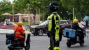 Robot-robot humanoid ini ditempatkan di persimpangan jalan utama dan area strategis, termasuk di sekitar kawasan wisata. Tampak dalam foto, orang-orang berkendara melewati robot polisi humanoid di Hangzhou, provinsi Zhejiang Timur, Tiongkok pada Minggu 3 Mei 2026. (Agatha CANTRILL/AFP)