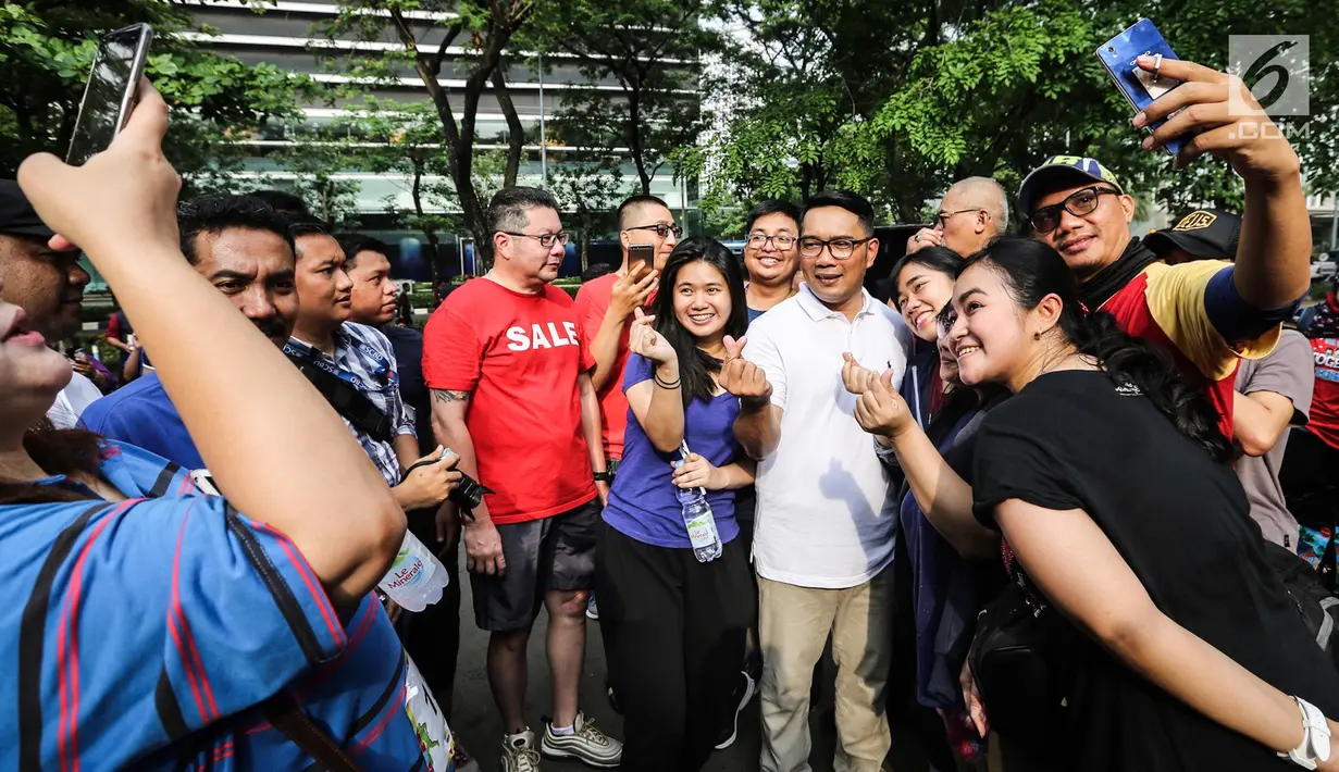 Gubernur Jawa Barat Ridwan Kamil berswafoto bersama warga saat acara Family Day Artha Graha Peduli (AGP) di Pasar Akhir Pekan SCBD, Jakarta, Minggu (25/11). Ridwan Kamil menyempatkan berolahraga sebelum bertolak ke Bandung. (Liputan6.com/Fery Pradolo)